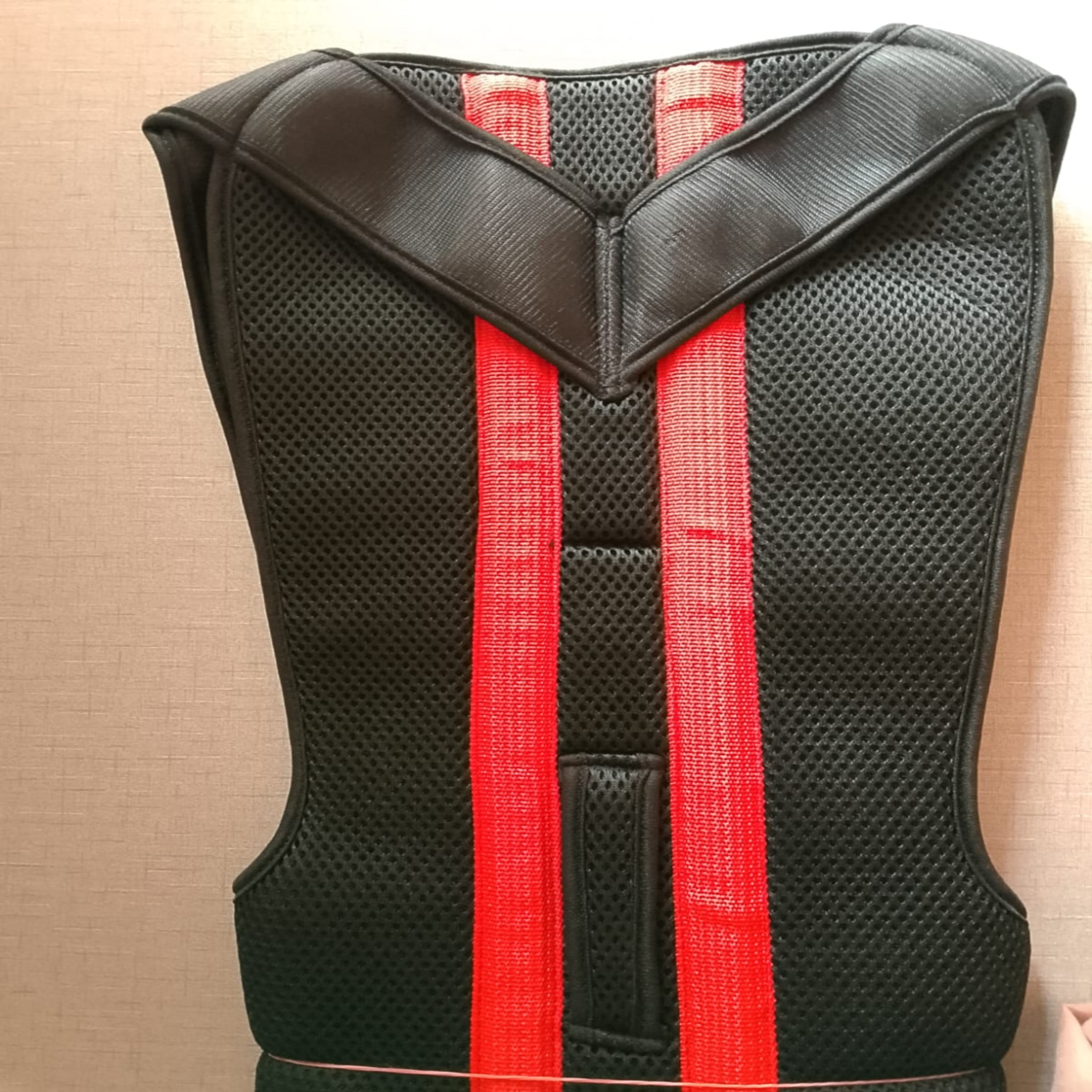Black protective vest with red straps on a beige background